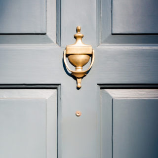 Blue front door with brass door knocker to illustrate property tenancy