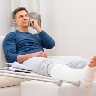 Man with cast on his leg sat on the phone