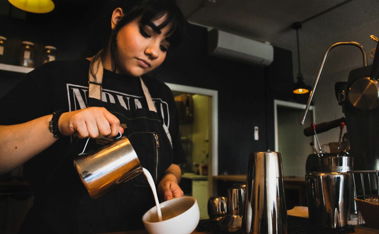 Young female worker making coffee behind a cafe counter