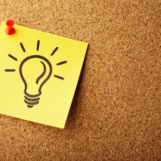 Post it note showing drawing of a light bulb, pinned onto a pin board