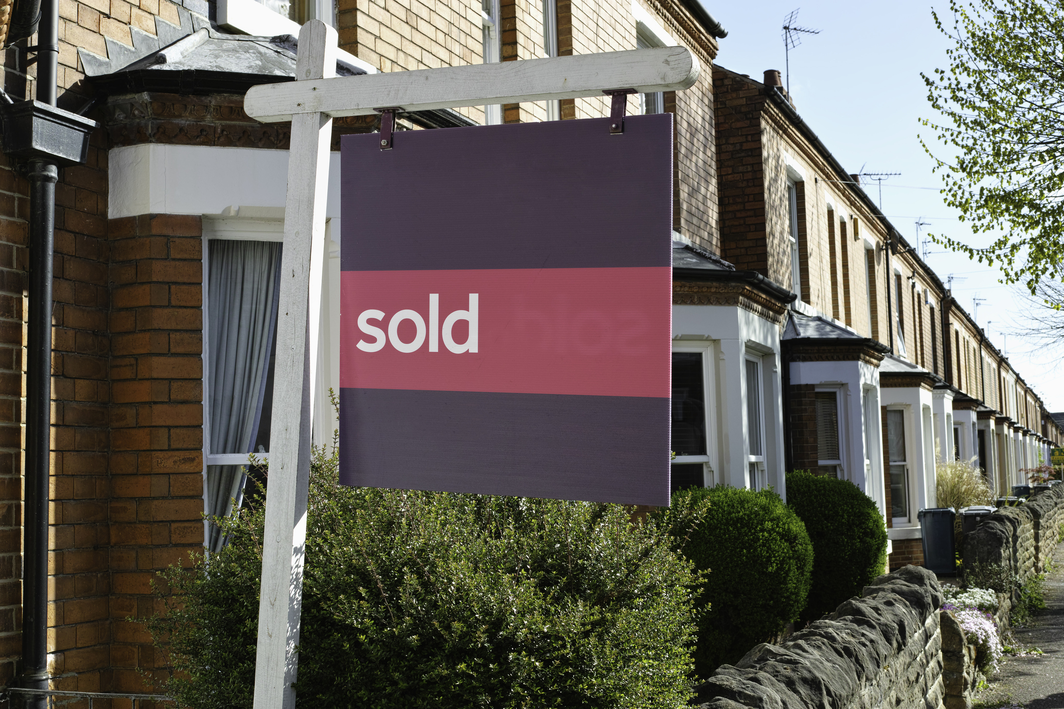 A 'sold' sign sits outside a row of terraced houses.