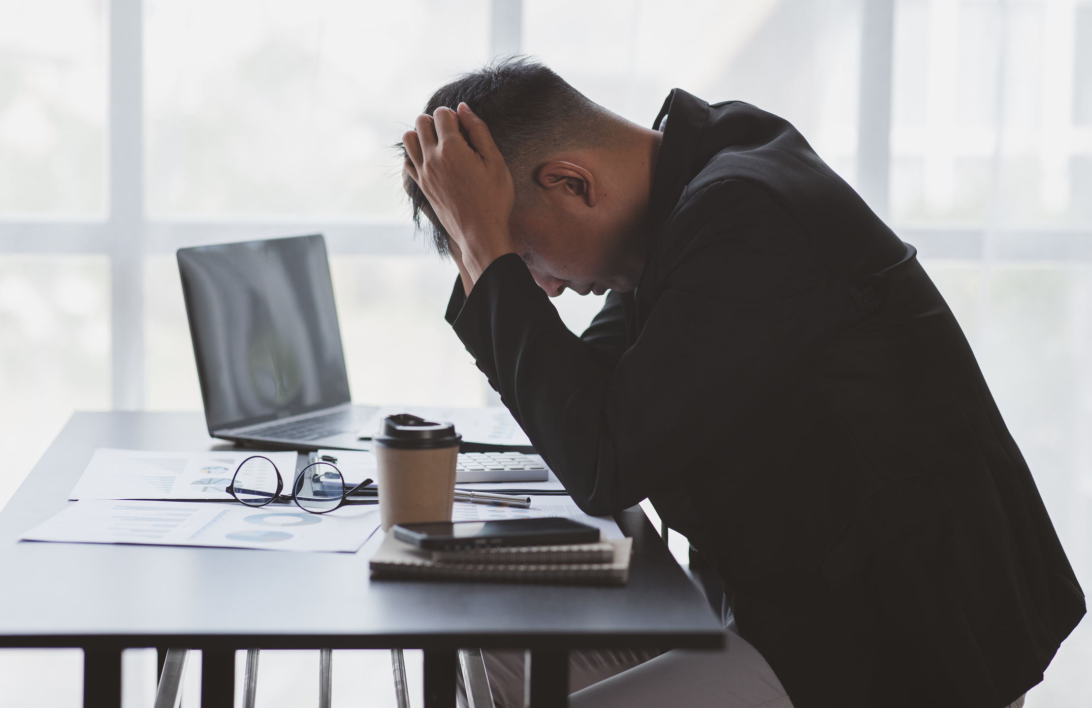 Discrimination at work. A man sits at his desk with his head in his hands