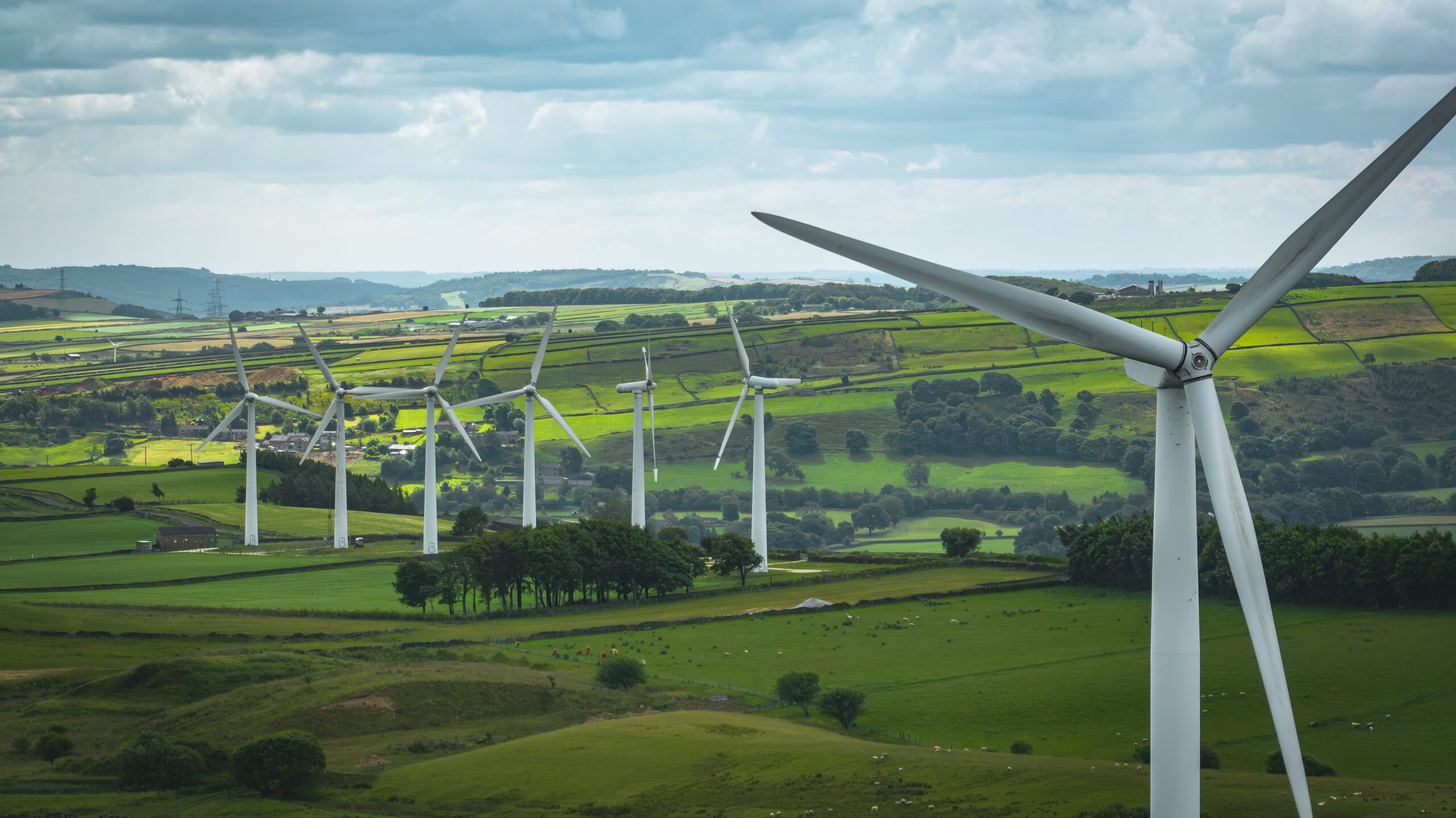 A renewable energy site showing miles of green fields and tall wind mills.